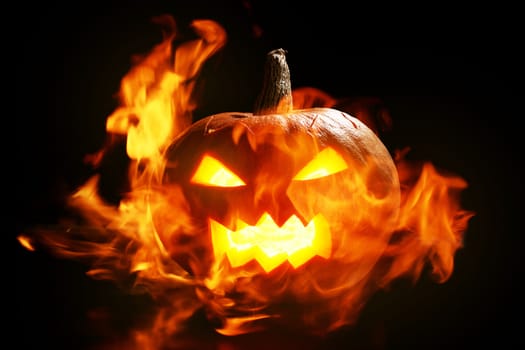 halloween pumpkin in fire over a black background