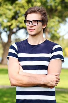 Portrait of young and smiling cute man with glasses in park