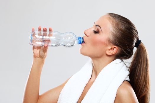 Fitness woman drink water after train on grey background