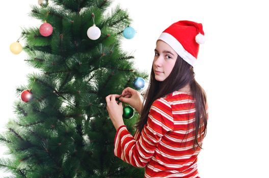 Young girl wearing beanie decorating christmas tree, eye contact, horizontal shot