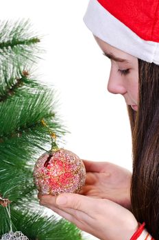 closeup portrait of young girl decorating christmas tree, holding red bauble, profile vertical shot