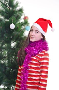 portrait of young girl wearing beanie, standing near christmas tree, eye contact, vertical shot 