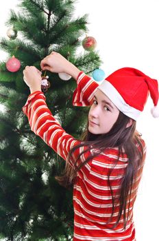 Young girl wearing beanie decorating christmas tree, eye contact, horizontal shot