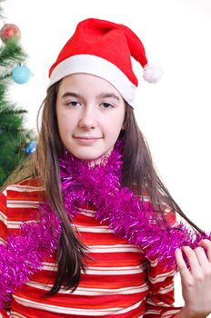 portrait of young girl wearing beanie, standing near christmas tree, eye contact, vertical shot 