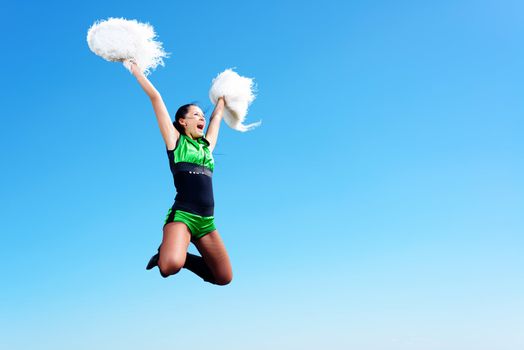 cheerleader girl jumping on a background of blue sky