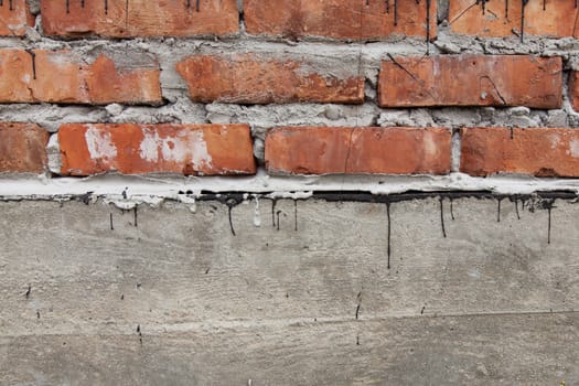 Closeup of a brick wall with concrete base