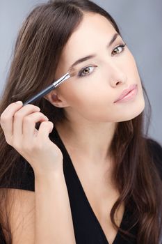 pretty woman applying make up with brush