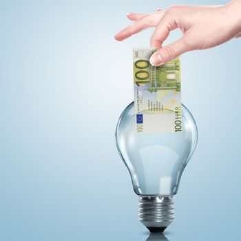 Hand and money inside an electric light bulb