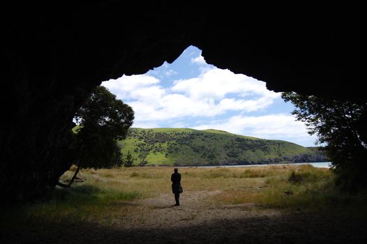 Man in front cave entrance, Okains Bay, Banks Peninsula, New Zealand