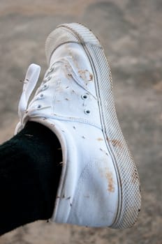 dirty white shoe with mud and burdock