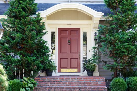 Magenta Home door bordered by two evergreen pine trees