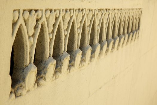 Beige wall with a section of ornate features or holes diminishing to the right