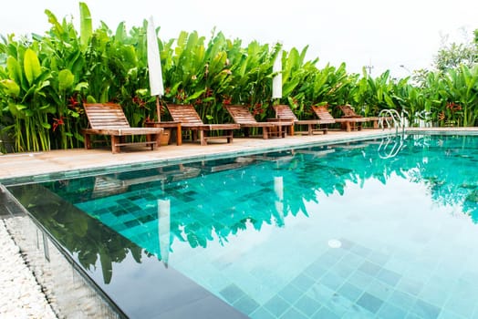 Small swimming pool with wooden setting surrounded by trees, taken on a sunny day