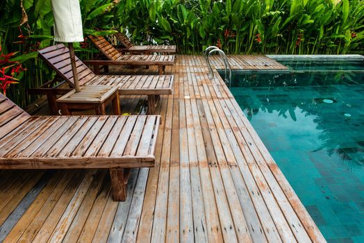 Small swimming pool with wooden setting surrounded by trees, taken on a sunny day