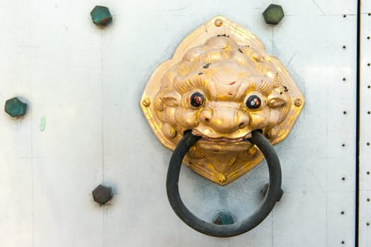Chinese temple golden door handle, on a grey metal door