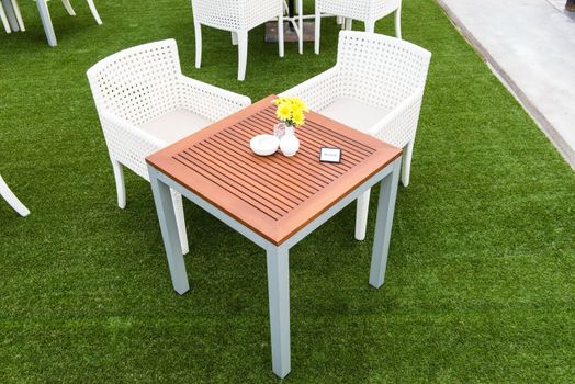 Tropical wooden dinning table on green grass with reserve sign on the table, taken on a cloudy day