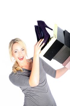Smiling blonde woman holding high heels and shoe boxes on white background