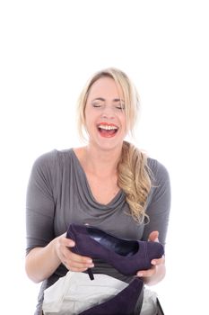 Excited happy blonde woman opening box of shoes with purple high heels on white background Olayful happy beautiful young model having a candid heartfelt laugh as she holds a fashionable court shoe she has just removed from the box isolated on white
