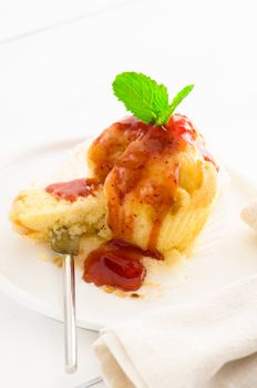 muffin with tasty strawberry sauce and fresh mint leaf on white plate