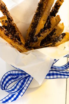 spicy puff pretzel sticks in a white cup with a blue ribbon as decoration on white wooden table