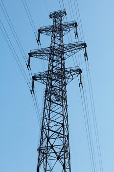 Power lines and electricity pylon  against blue sky