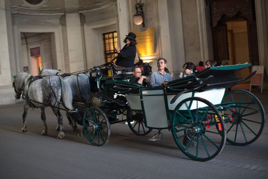 VIENNA - OCTOBER 3: Traditional horses and carriage (also called Fiaker) driving through the famous Hofburg on October 3, 2012 in Vienna, Austria. The Fiaker rides are a traditional tourist attraction -200 carriages are available each day in this city.