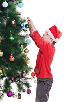 Young boy wearing santa hat decorating christmas tree, vertical shot