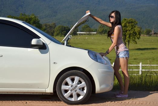 Worried young woman with her broken car