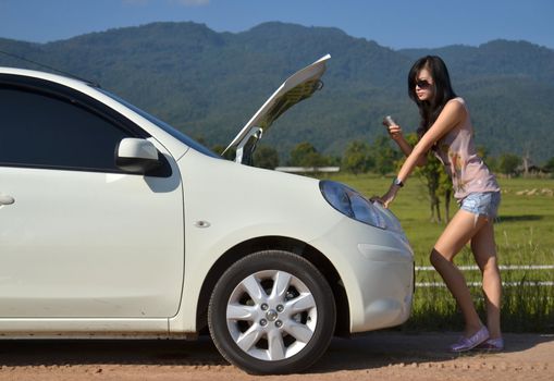 Worried young woman with her broken car