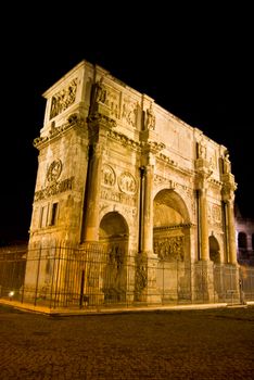 famous triumphal arch standing next to the colosseum in Rome at night