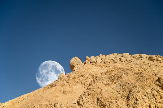 Full moon setting over the rocky desert in Egypt