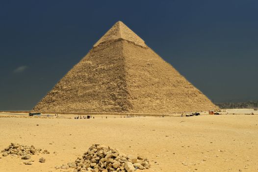 A row of camels transport tourists in front of all of the Giza Pyramids in Cairo, Egypt