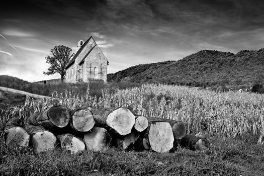 Stone mountain church and pile of chopped trees in black & white, Kalnik, Croatia