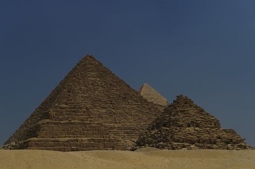 A row of camels transport tourists in front of all of the Giza Pyramids in Cairo, Egypt