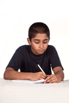 An handsome Indian kid doing his homework diligently, with ample copyspace