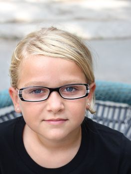 Beautiful, serious child looking at the camera, wearing glasses
