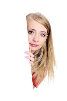 Smiling blond woman peeping from behind a blank card. Isolated on white.