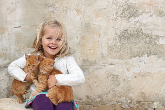 A happy girl holding a pair of cats. Space for free text