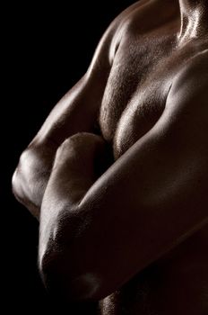 Athletic male torso in dark key. Focus on the chest.