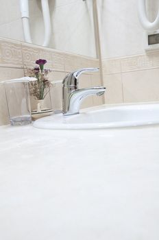 White sink, chrome tap and two glasses in a hotel bathroom