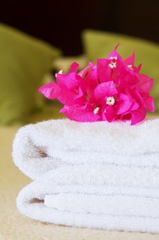 White towels with flowers on a bed in a hotel room. Selective focus on flowers.