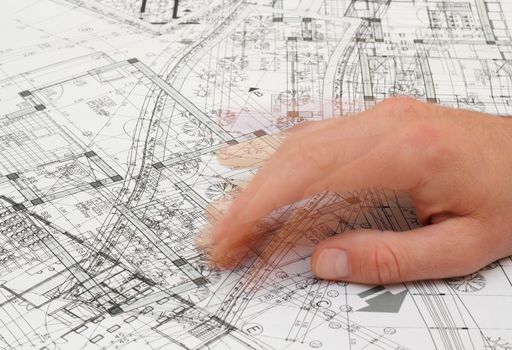architect shaking his fingers as he searches a solution out of a very messy blueprint