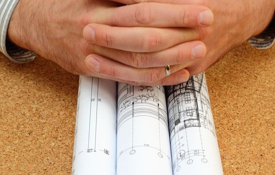 human hands over architectural work - rolled blueprints over the office