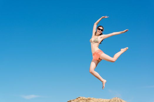 beautiful young woman jumping on a background of blue sky, having a fun time