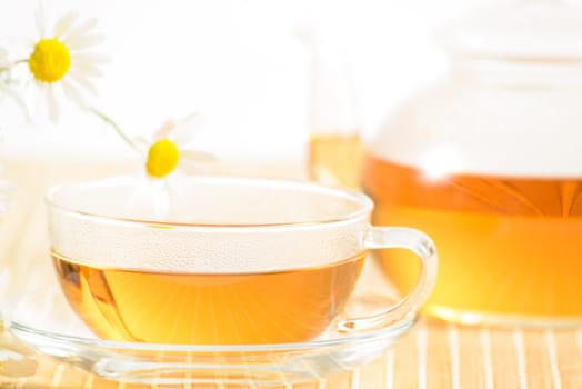 A teacup and a teapot with herbal chamomile tea