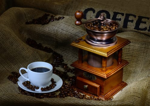 Coffee Mill with beans, cup and burlap. still life