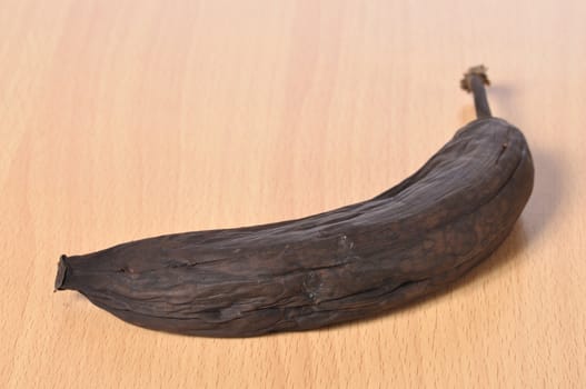 Closeup of over ripe black banana on wooden floor