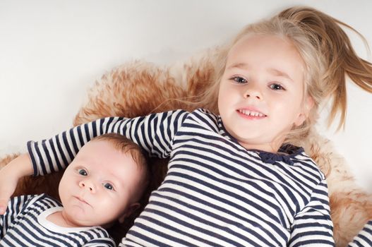 Shot of newborn baby with sister lying on fur