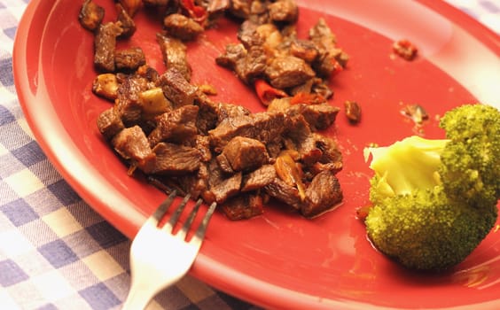 fried beef and brocolli served on a red plate