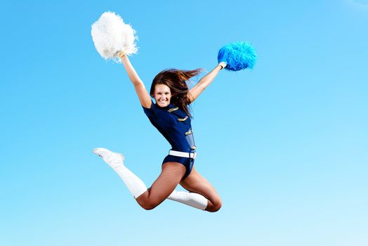 cheerleader girl jumping on a background of blue sky